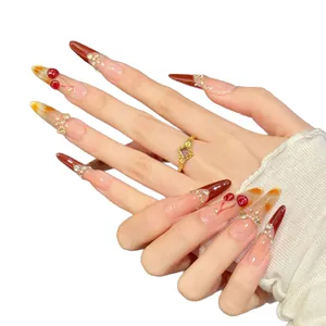 Long pointed press-on nails with cherry red gradients, glitter, and 3D fruit accents