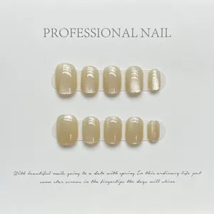 Unghie finte cat-eye oro champagne su cartoncino bianco in forma rotonda corta ed elegante
