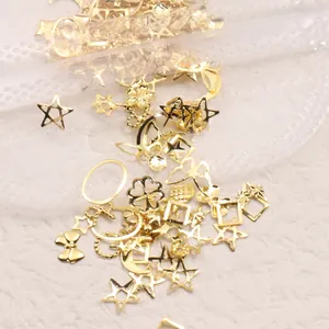 Primer plano de dijes metálicos dorados para uñas con formas de estrella luna y mariposa