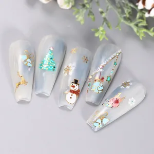 Macro shot of long trapezoid Christmas nail stickers with gold deer and snowflake motifs