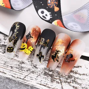 Détail de faux ongles d'Halloween en noir mat avec des motifs de fantômes en feuille dorée