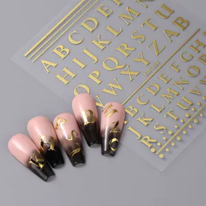 Détail d'autocollants alphabet dorés avec effet relief métallique sur des ongles
