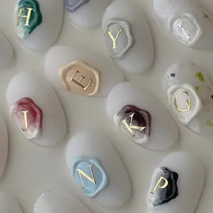 Détail macro de stickers d'ongles en sceau de cire 3D avec lettres métalliques dorées