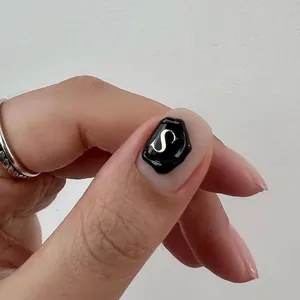 Détail d'un autocollant nail art sceau de cire vintage avec lettre S dorée sur noir