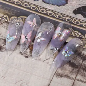 Gros plan sur de longs ongles stiletto avec marbre violet, papillons et strass argentés