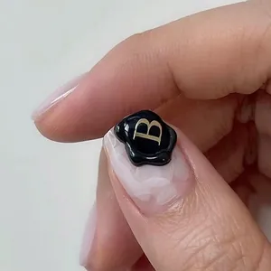 Vue macro d'un autocollant pour ongles sceau de cire noir avec lettre B dorée