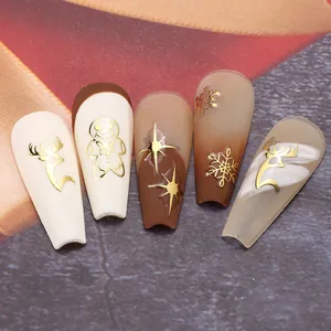Makroaufnahme von 3D-Weihnachtsnagelstickern mit goldenen Rentier- und Lebkuchenmotiven