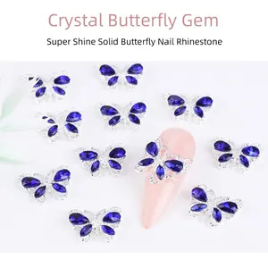Macro shot of silver alloy butterfly nail charms with blue crystals on pink manicure tips