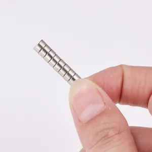 Stack of silver cylindrical strong magnets held by fingers against a white background