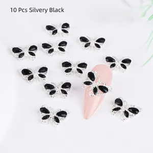Macro shot of 10pcs silver butterfly nail charms with black rhinestones on a fake nail