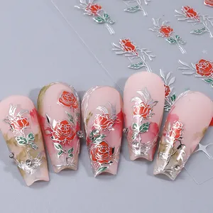 Macro view of 3D nail stickers featuring red roses with silver outlines and leaf details