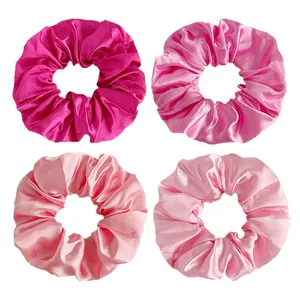Detailed view of four satin silk scrunchies in various shades of gradient pink