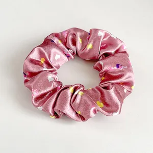 Dettaglio dell'elastico in raso rosa con motivi a cuore colorati e trama a pieghe