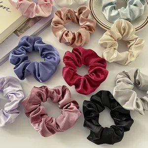 Lustrous satin scrunchies in various colors displayed on a decorative ceramic dish