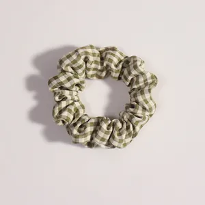 Dettaglio dell'elastico scrunchie in tessuto a quadretti verdi e bianchi con pieghe morbide