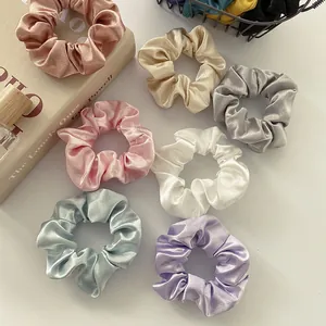 Elegant set of seven satin scrunchies in pastel colors on a minimalist white background