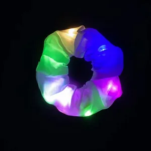 Makroaufnahme von LED-leuchtendem Satin-Haargummi mit bunten Lichtperlen auf schwarzem Grund