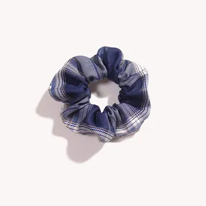 Dettaglio ravvicinato dell'elastico scrunchie a quadri blu scuro con trama scozzese