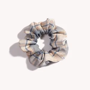Dettaglio dello scrunchie a quadri blu e beige con consistenza morbida ed elastica