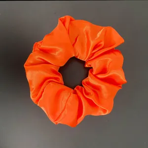Nahaufnahme eines leuchtend orangefarbenen Satin-Haargummis mit feiner Stoffstruktur