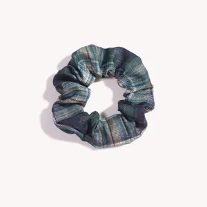 Dettaglio dell'elastico per capelli in stile scozzese con trama tartan verde e alta elasticità