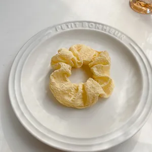 Dettaglio di un morbido elastico giallo pallido su un piatto di ceramica bianca