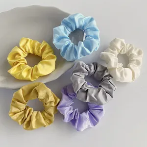 Set aus sechs bunten Satin-Haargummis in Pastelltönen auf minimalistischem weißem Grund