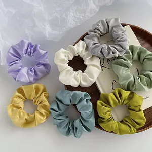 Set aus sieben bunten Satin-Haargummis in Pastelltönen auf einem Dekoteller