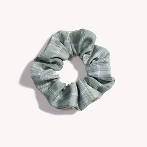 Dettaglio di elastico per capelli a scacchi grigio-verde e bianco con trama in tessuto