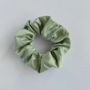 Nahaufnahme von hellgrünem Satin-Haargummi mit weicher Seidentextur und glänzendem Finish