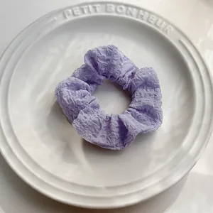 Dettaglio macro dello scrunchie lavanda stropicciato su un piatto decorativo in ceramica