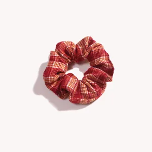 Dettaglio della trama del tessuto a quadri rosso e arancione e cuciture dello scrunchie