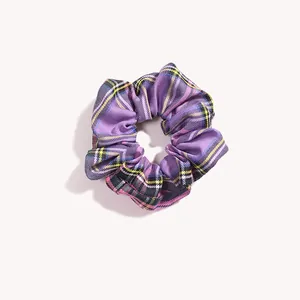 Dettaglio di elastico per capelli in tessuto a quadri viola con motivi gialli e bianchi