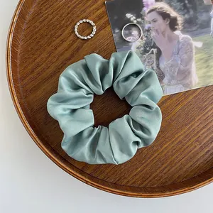 Detail eines mintgrünen Satin-Haargummis mit glatter Seidentextur und elastischem Design