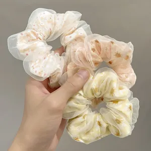 Three daisy printed floral organza scrunchies in beige, light pink and yellow