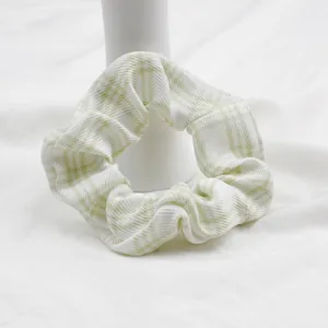 Dettaglio dell'elastico scrunchie a quadretti bianchi e verdi con trama a pieghe morbide