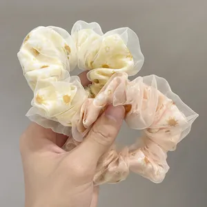 Detail of yellow and orange daisy print mesh scrunchies with soft tulle layering