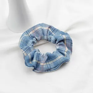 Dettaglio dell'elastico per capelli a quadri blu su sfondo di cotone bianco pulito