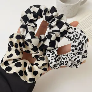 Close-up of three stylish scrunchies featuring leopard, polka dot, and checkerboard patterns
