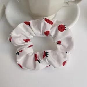 Primo piano di elastico per capelli in chiffon bianco con motivo a fragole rosse e foglie verdi