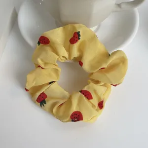 Dettaglio di un elastico in chiffon giallo con stampa fragole e una tazza da caffè