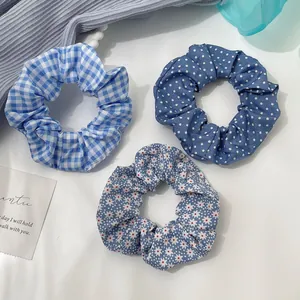 Detailed view of three blue fabric hair scrunchies with plaid and polka dot patterns