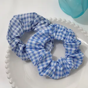 Set of two light blue and white checkered fabric scrunchies on a white ceramic tray