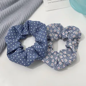 Close-up of blue polka dot and floral scrunchies on a soft textured grey background
