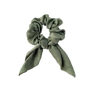 Détail d'un chouchou en satin vert sauge avec un élégant nœud en oreilles de lapin