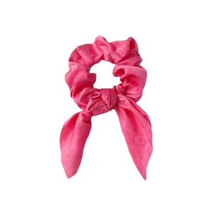 Gros plan détaillé sur le chouchou en satin rose vif avec nœud oreilles de lapin