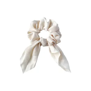 Détail du chouchou en satin crème avec longs rubans et texture de soie douce