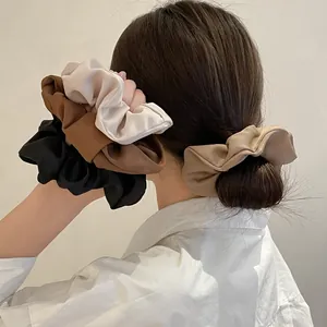 Zijdeachtige satijnen scrunchies in aardetinten getoond op model voor paardenstaarten