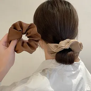 Detailweergave van satijnen scrunchies in koffie en melkthee op haar en hand