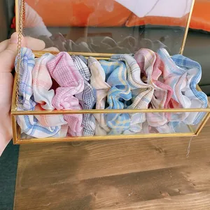 Dettaglio di elastici scrunchie a quadri colorati in una scatola di vetro dorata